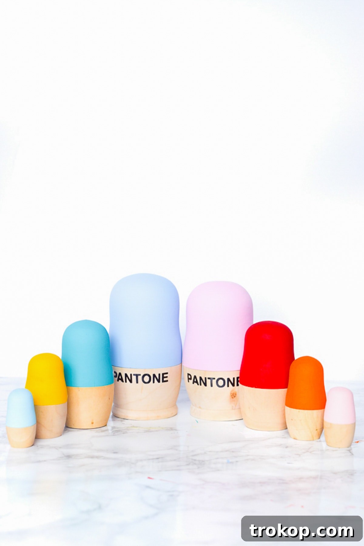 A completed set of DIY Pantone nesting dolls displayed together, showcasing a vibrant array of colors and the iconic 'PANTONE' lettering on each doll.