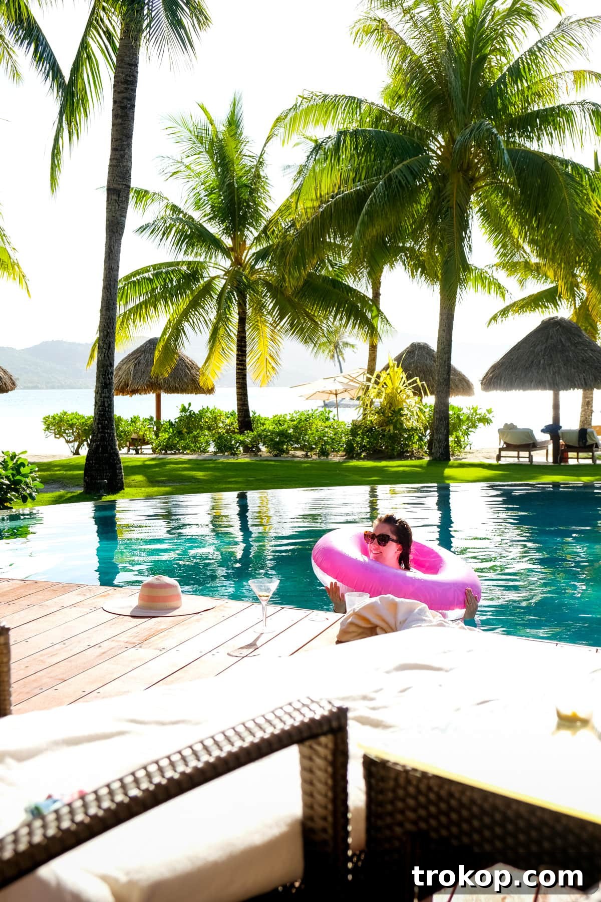 Woman posing elegantly on the edge of an overwater bungalow with lagoon views