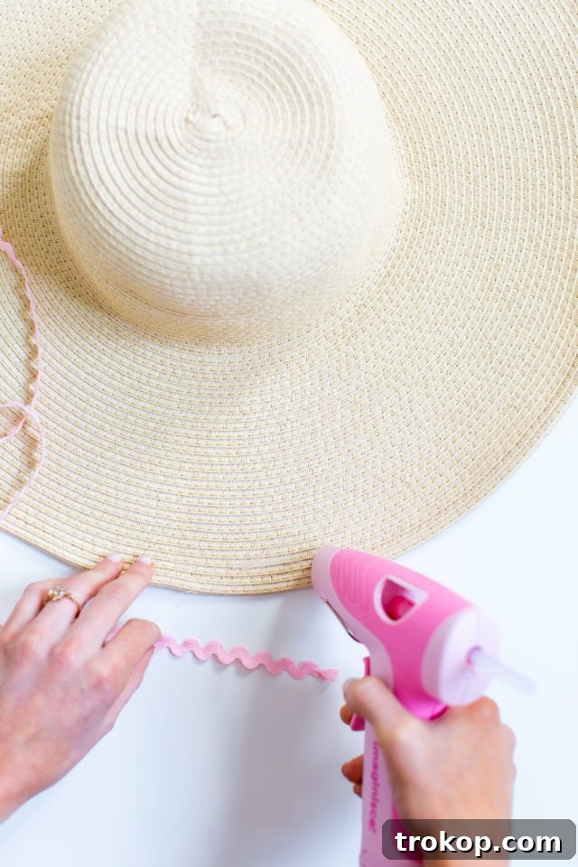 Close-up of materials for DIY ric rac sun hat: straw hat, colorful ric rac, and glue gun