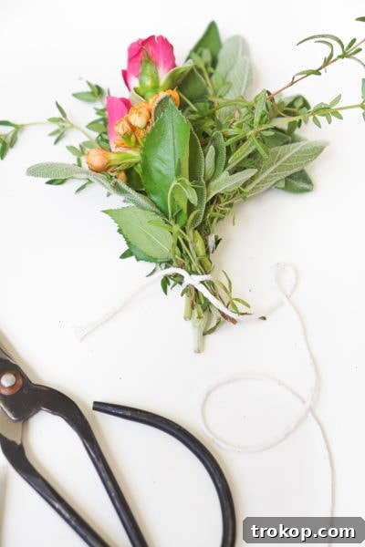 A close-up of how to string twine around a fresh herb bundle, showing the initial securing step for the incense bundle.
