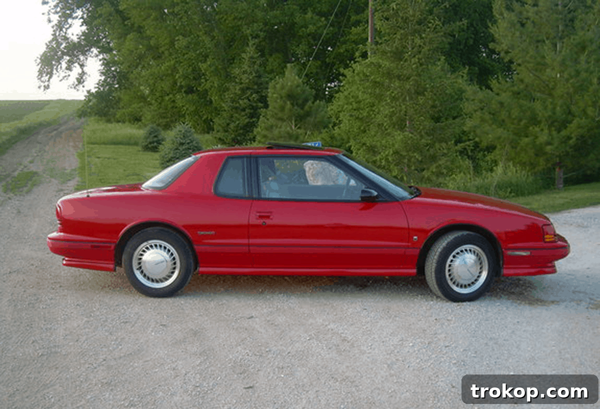 A 1992 Oldsmobile Toronado in maroon, the author's first car, a symbol of early driving experiences and independence.
