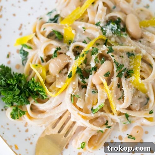 A bowl of creamy Roasted Garlic White Bean Alfredo pasta, garnished beautifully.