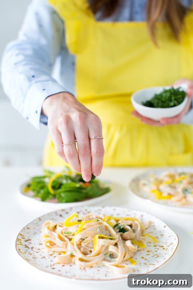 Freshly drained fettuccine pasta with yellow carrot ribbons and wilted spinach in a colander.