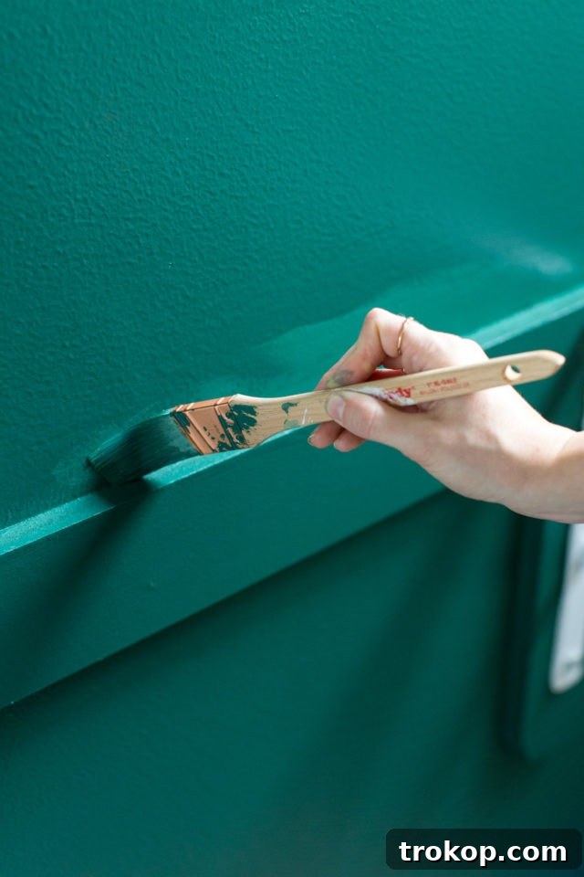 Person painting the accent wall in the home office nook with BEHR Equilibrium T18-20 green paint