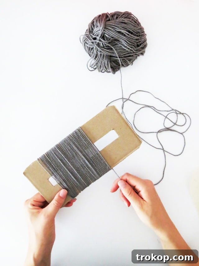 Boho Yarn Fringe Pillow Project 8 Wrapping yarn around the cardboard template for fringe