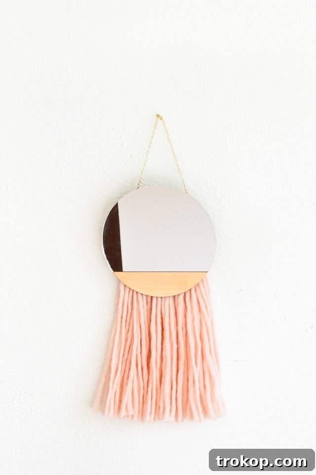 Close-up of the DIY Fringed Mirror Wall Hanging showing the intricate yarn fringe and gold paint detail.