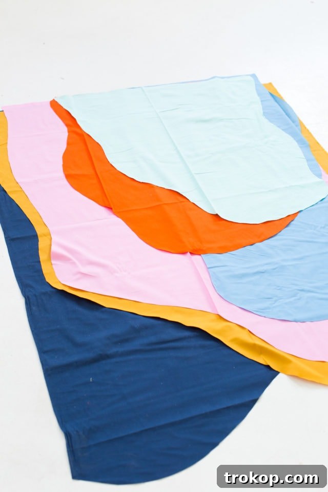 Hands cutting abstract fabric shapes for a DIY wall hanging, demonstrating the layering technique
