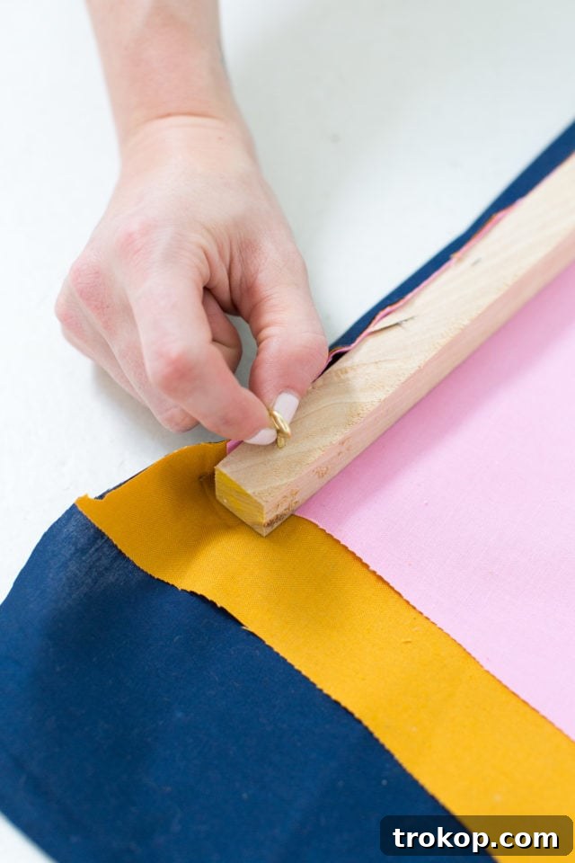 Gold eye hooks and cording added to the wooden dowel rod for hanging a DIY fabric wall art piece