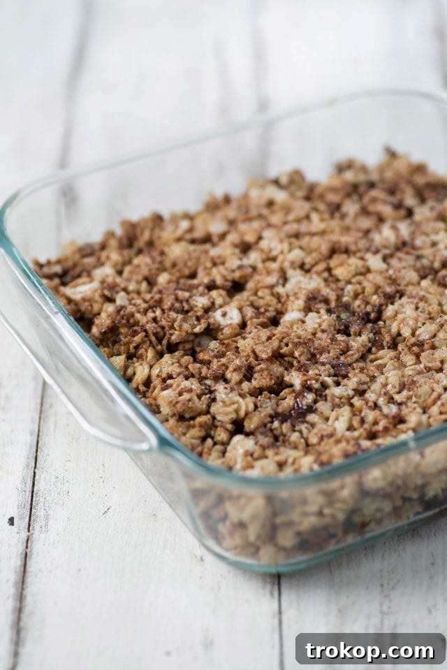 Campfire S'mores Krispie Delights 5 Rice Krispie Treat mixture being pressed into a baking pan