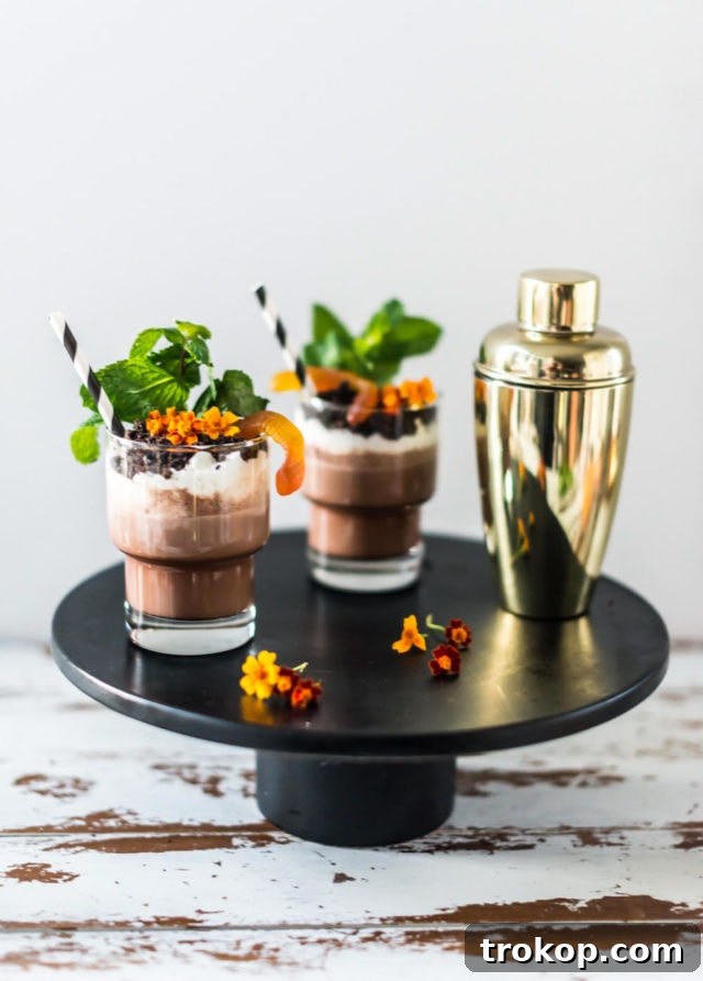 Three Boozy Dirt Cups garnished with gummy worms and fresh mint