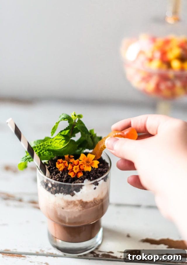 Hands preparing the layers of a Boozy Dirt Cup