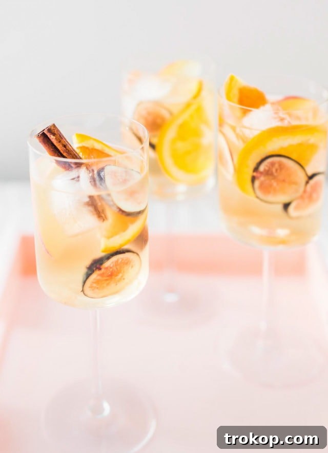 Autumn Fig Apple Cider Sangria 5 A close-up shot of a pitcher filled with Fig Apple Cider Sangria, showing the beautiful arrangement of sliced fruits and cinnamon sticks.