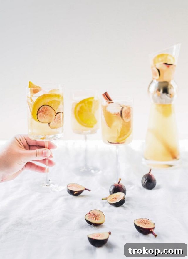 Autumn Fig Apple Cider Sangria 6 A glass of white wine sangria with figs, apples, and oranges, served over ice and garnished with a cinnamon stick.