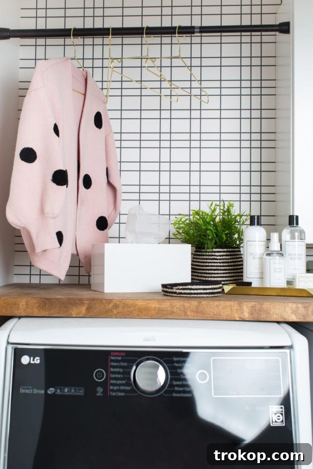 A clean and styled corner of the laundry room with the DIY dryer sheet dispenser and decorative items