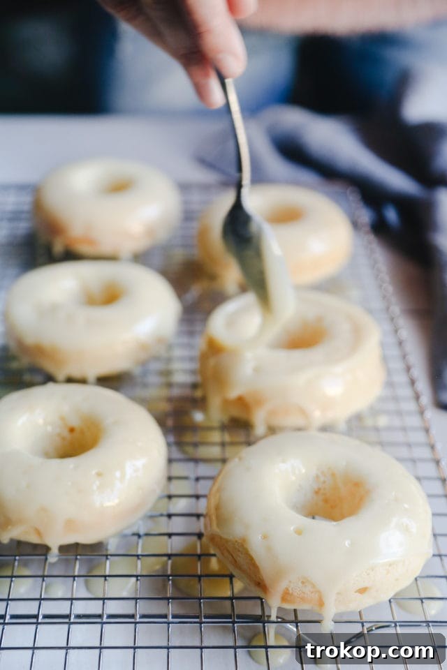 Champagne Infused Doughnuts with Velvety White Chocolate Glaze 9 White chocolate glazed Champagne Donuts with sprinkles on a wire rack by Ashley Rose of Sugar and Cloth