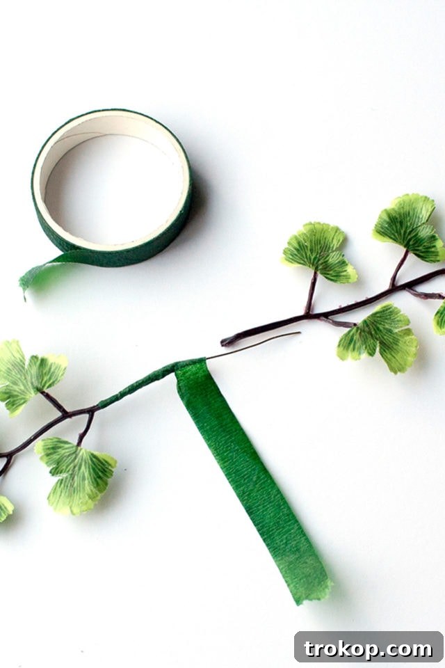 Shimmering Gold DIY: Wreaths & Garlands 7 Step 2: Using floral tape to attach artificial leaves to wire pieces, forming flexible stems.