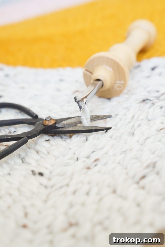 How to Make a Rug Hooked Pillow 13 Step 7: The punch needle lifted slightly from the fabric, preparing to trim the yarn.