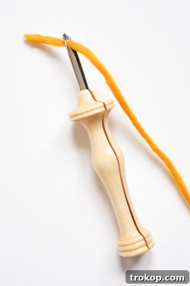 How to Make a Rug Hooked Pillow 8 Step 2: Threading a punch needle with yarn, demonstrating proper placement through the tip.