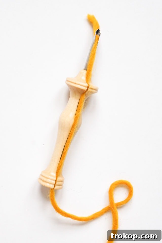 How to Make a Rug Hooked Pillow 9 Step 3: Showing how the yarn is correctly seated in the wooden channel of the punch needle handle.