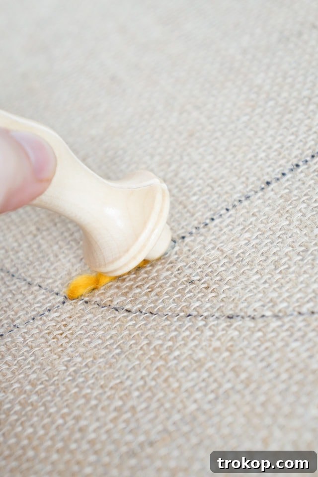 How to Make a Rug Hooked Pillow 10 Step 4: Demonstrating the initial insertion of the punch needle into the burlap fabric.