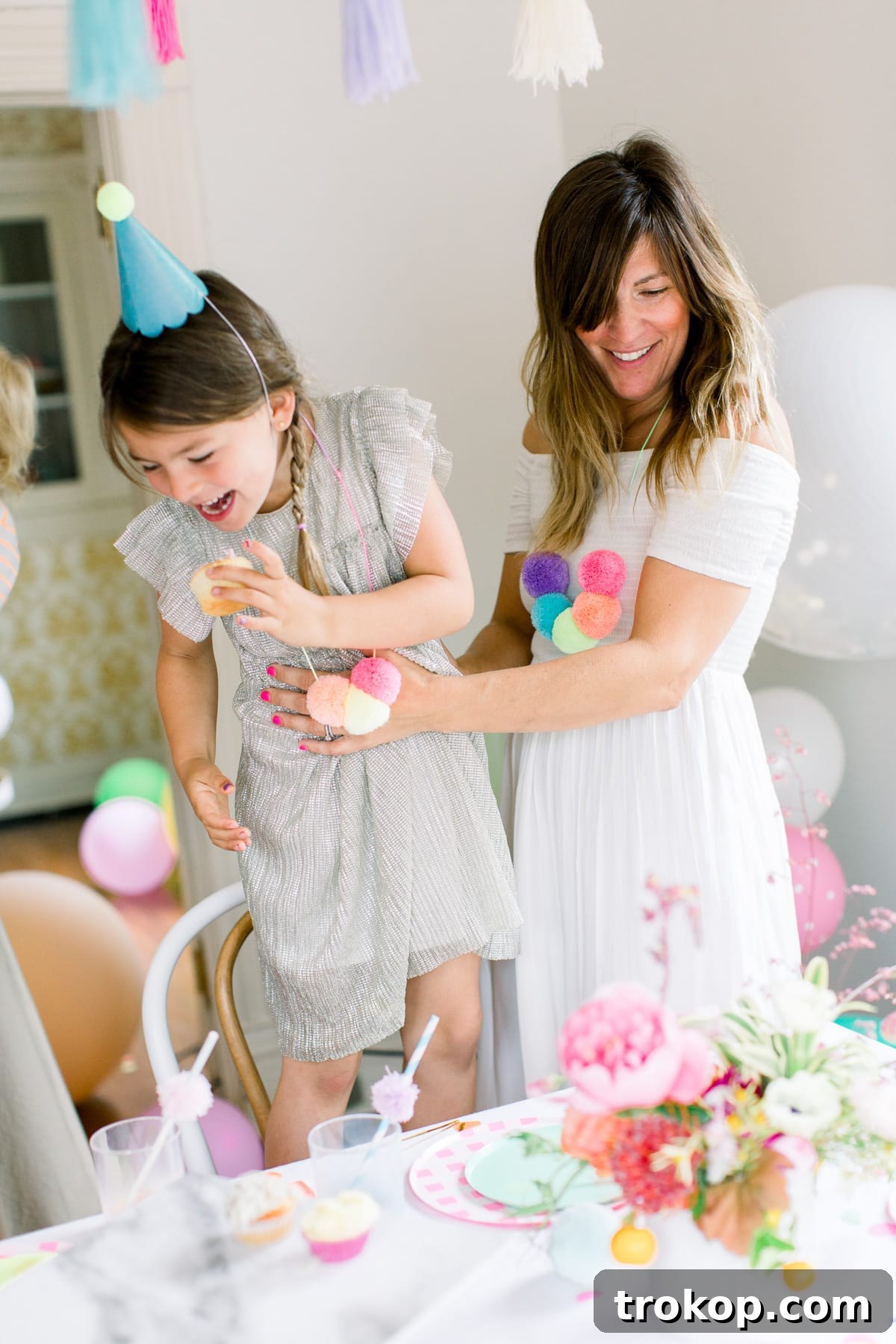A vibrant display of a colorful pom pom birthday party, featuring cheerful decorations and party supplies from Sugar & Cloth and Shop Leo. Perfect for kids' birthday party inspiration.