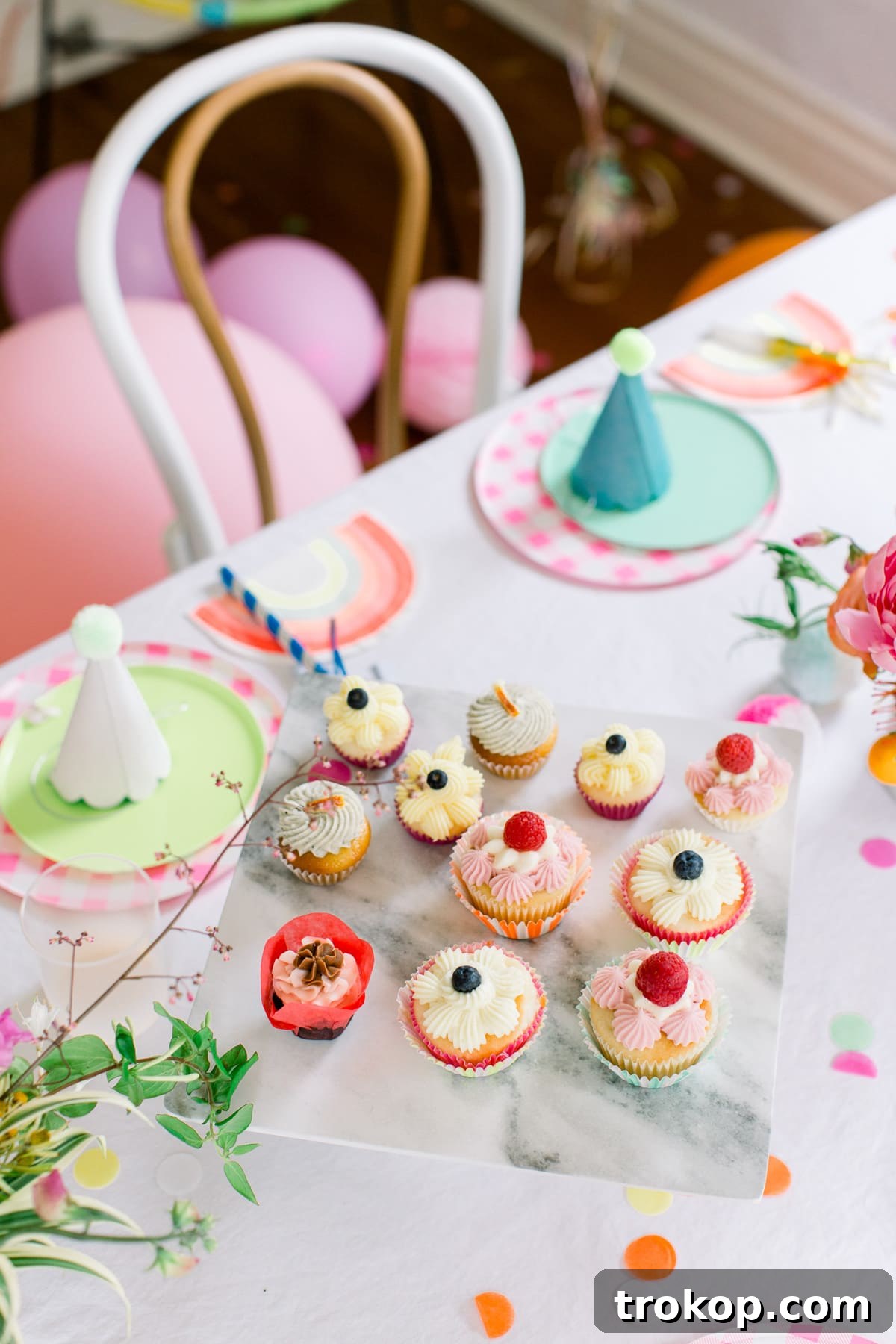 A vibrant tablescape featuring Meri Meri rainbow napkins and whimsical party hats, adding a playful touch to the colorful pom pom birthday theme.