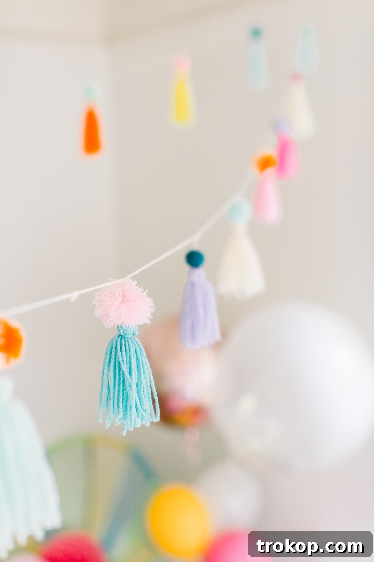 An inviting view of the entire party area, showcasing the harmonious blend of pom poms, garlands, balloons, and carefully chosen partyware, creating a festive environment.
