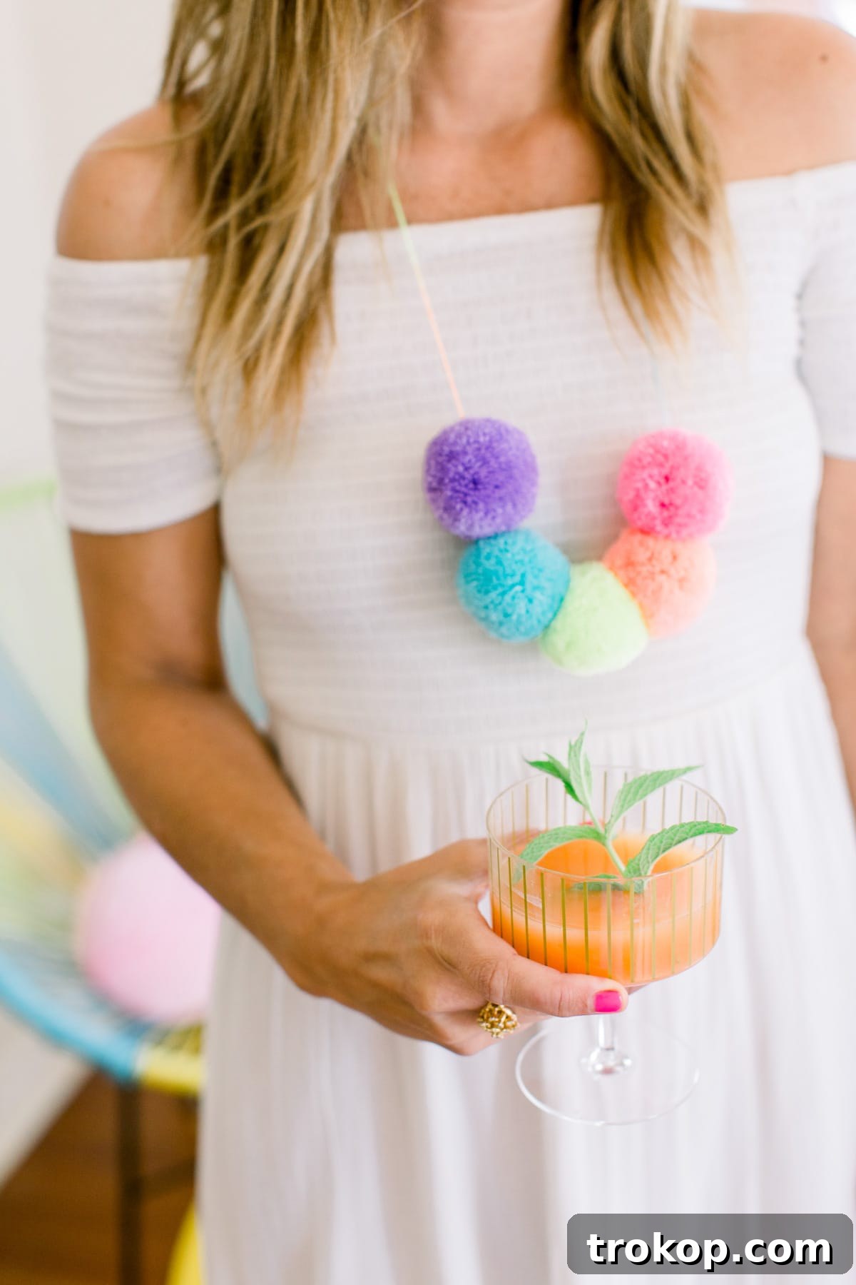 A wide shot showcasing the whimsical table setting of the pom pom birthday party, with striped plates, colorful cups, and creative decorations.