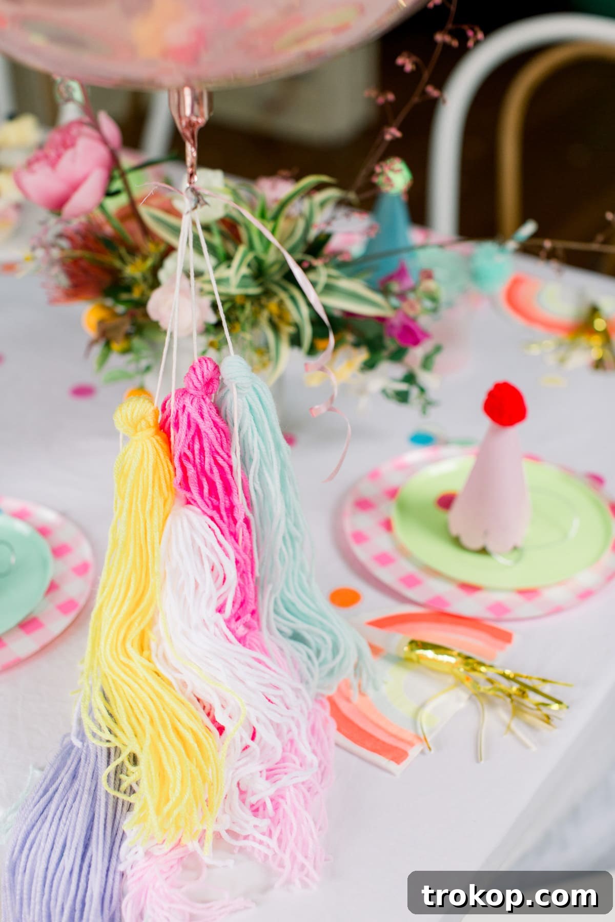 A vibrant birthday cake adorned with colorful sprinkles and a whimsical topper, centerpiece of the pom pom themed celebration.