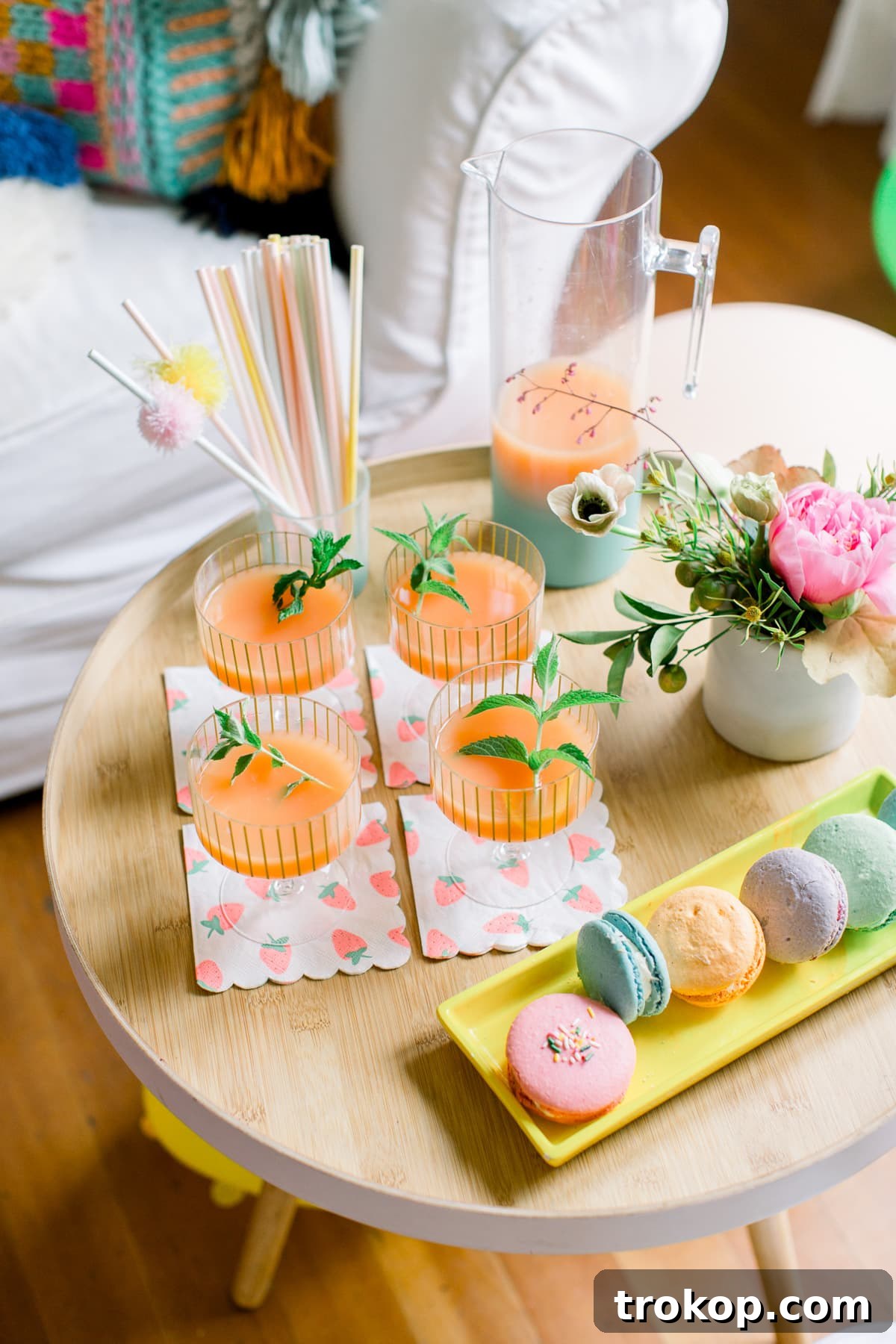 Close-up of a tiered display of colorful cupcakes from Farmhouse Frosting, each topped with vibrant frosting and sprinkles, next to Sugar & Cloth cupcake stands.