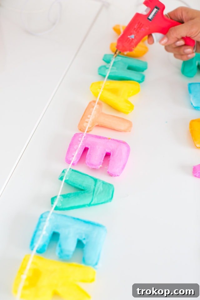 Tutorial step: gluing finished faux balloon letters onto string to create a charming garland