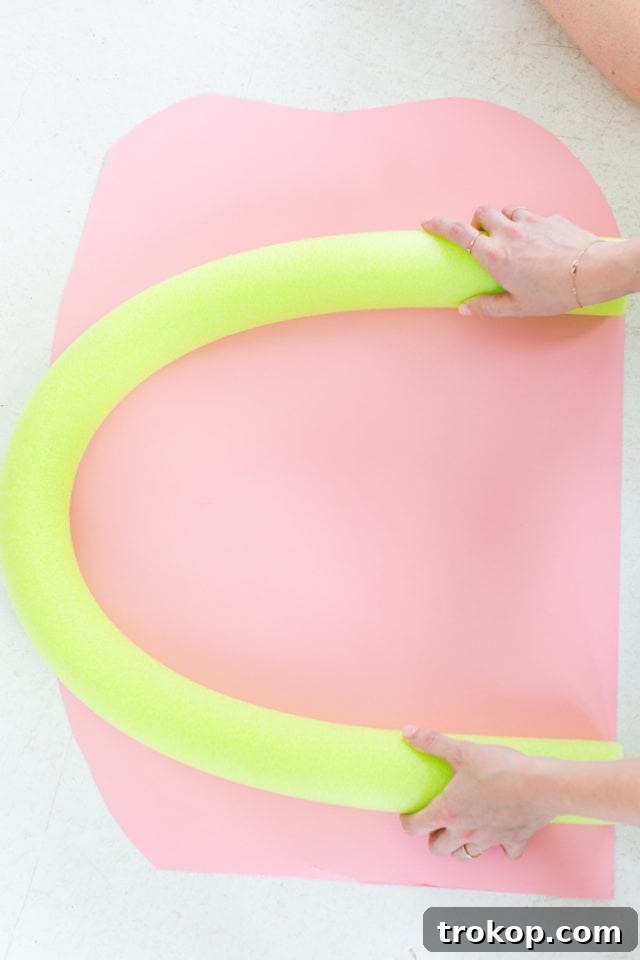 Wrapping a pool noodle with vibrant crepe paper for the DIY Rainbow Art Wall Hanging project.