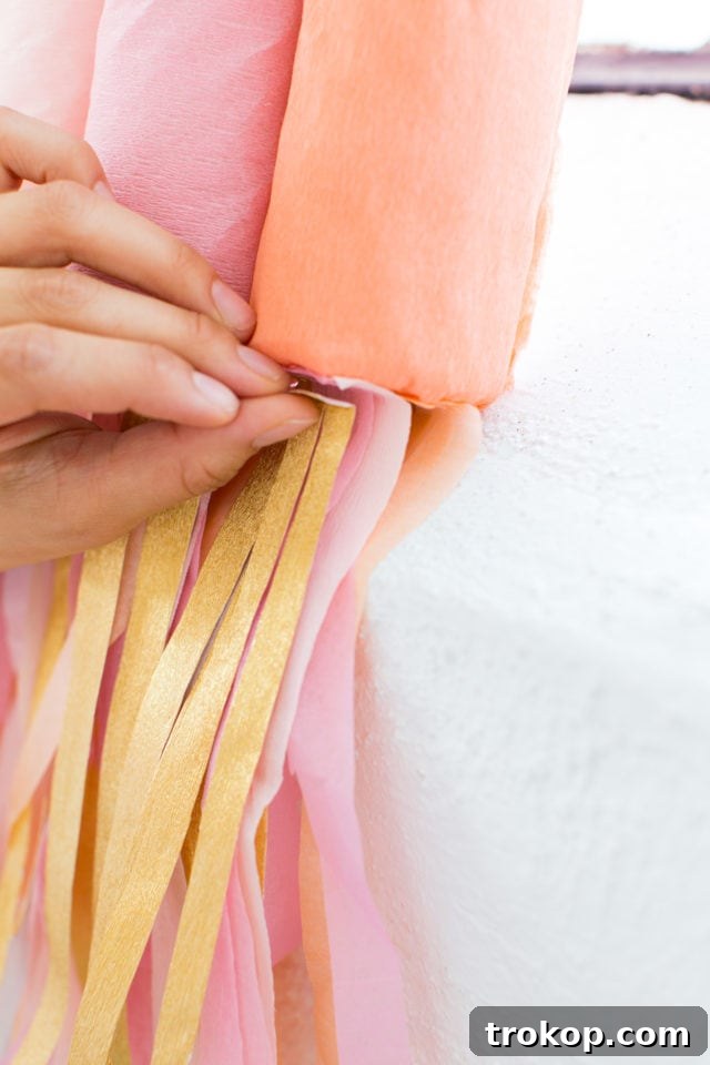Cutting colorful crepe paper strips to create fringe for the DIY Rainbow Art Wall Hanging.