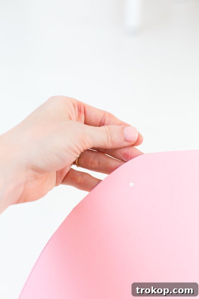 Attaching the colorful crepe paper fringe to the bottom of the DIY Rainbow Art Wall Hanging.