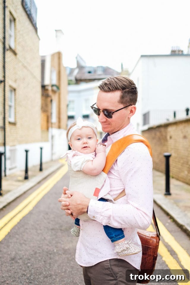 Stress-Free Baby Travel: Your 13-Item Packing Checklist 3 A mother holding her baby in a wrap during a stroll in Kensington, London, showcasing family travel ease.