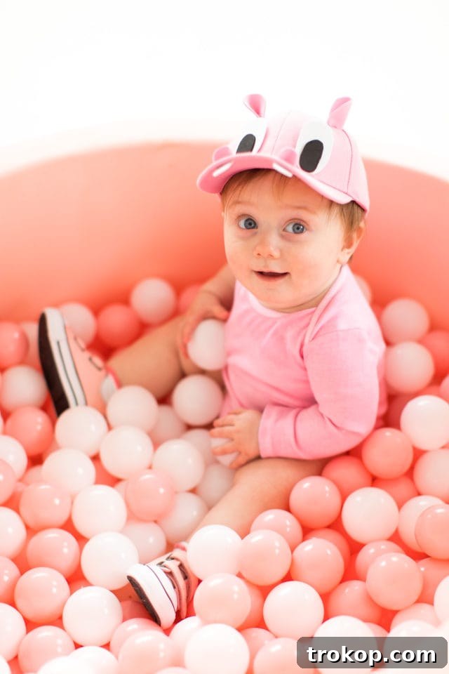 Our Handmade Hungry Hippo Crew 4 Gwen, the baby, adorably nestled in her pink felt ball pit, looking like the sweetest hungry hippo, as part of the family's DIY Hungry Hungry Hippos costume. The image captures a charming moment from this creative and unique family Halloween costume idea.