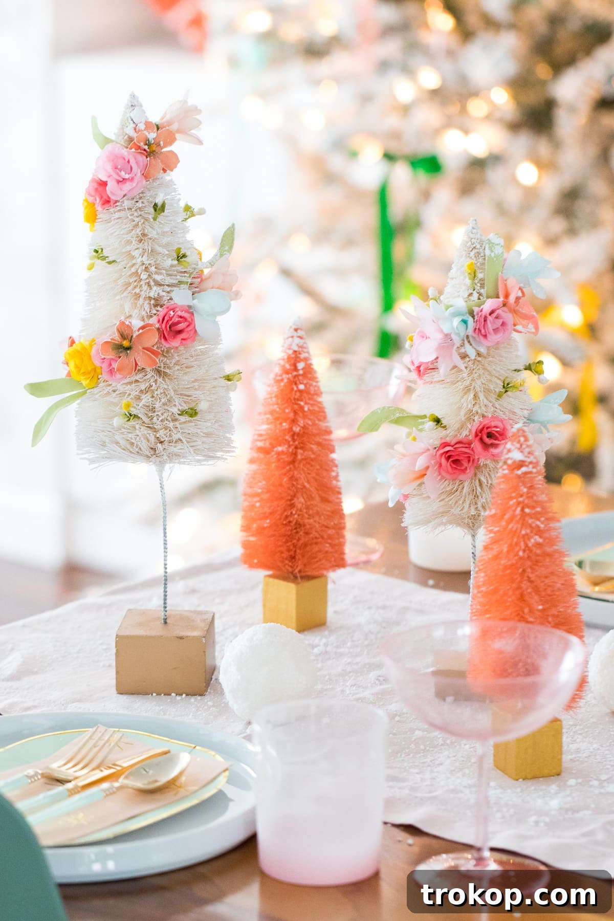 Charming DIY Floral Bottle Brush Christmas Table Decor 2 Vibrant faux flower bottle brush trees arranged with white ones, creating a festive holiday centerpiece.