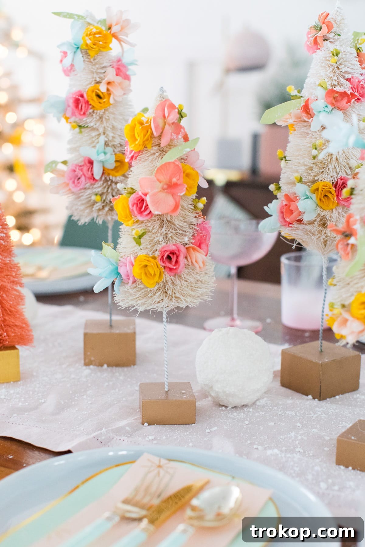 Close-up of a faux flower bottle brush tree, beautifully adorned with colorful faux blossoms and mixed with white decorative snowballs.