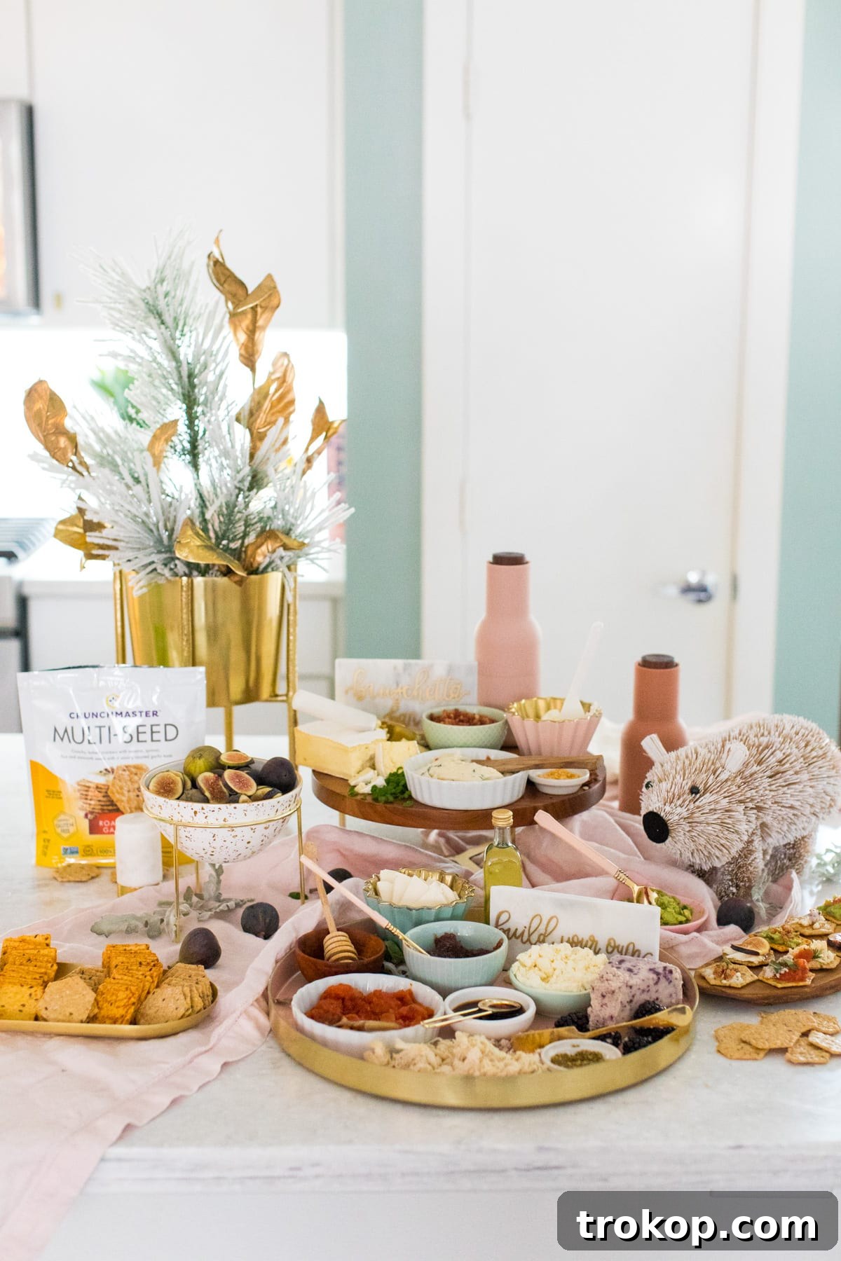 A beautifully styled interactive bruschetta bar with festive winter decor, featuring an array of fresh toppings and Crunchmaster crackers, perfect for entertaining guests.