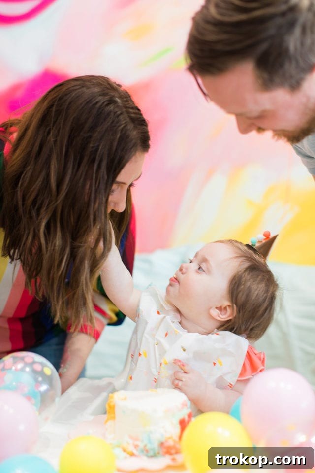 Gwen enjoying her smash cake, surrounded by colorful party decor