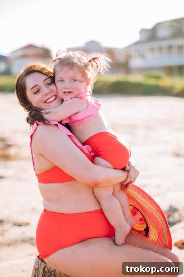 Gwen, Ashley Rose's daughter, playing in the confetti print rash guard, demonstrating its sun-protective qualities and adorable design from the Olivia + Ocean collection.
