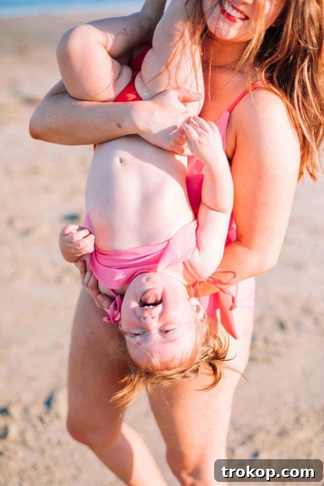 Ashley Rose of Sugar & Cloth posing in the coral red and perfect pink color block mom bod one-piece swimsuit, showcasing its retro style and flattering fit.