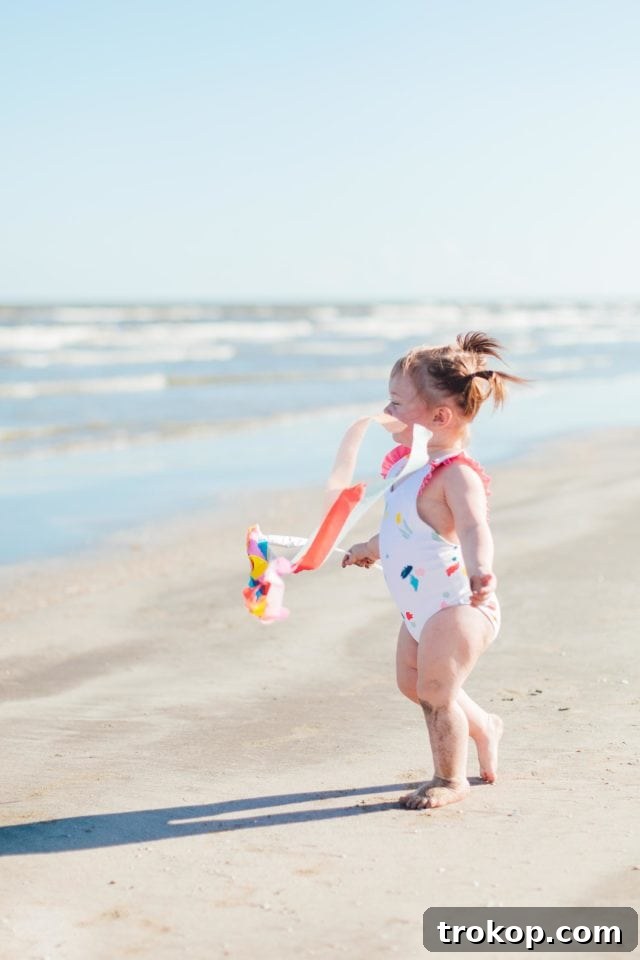 Gwen, daughter of Ashley Rose, smiling in a pink ruffled confetti one-piece swimsuit from the Olivia + Ocean collaboration, showcasing its playful design and comfortable fit.
