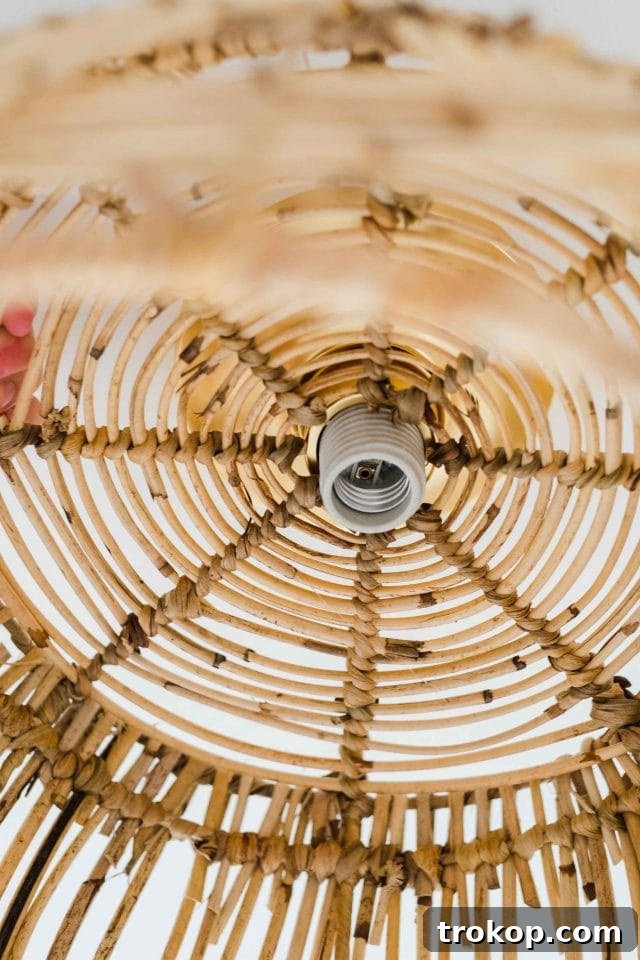 Woven Basket Pendant Light 9 Carefully slipping the prepared woven basket over the light bulb socket of the ceiling-mounted fixture.