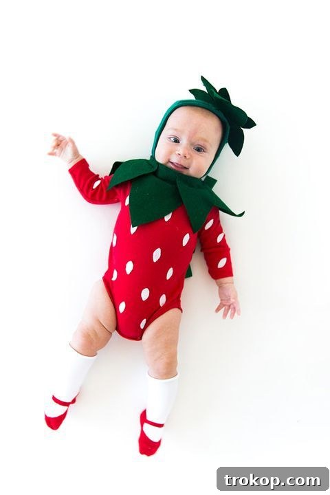 Adorably dressed baby in a DIY Strawberry Halloween costume with green felt leaves