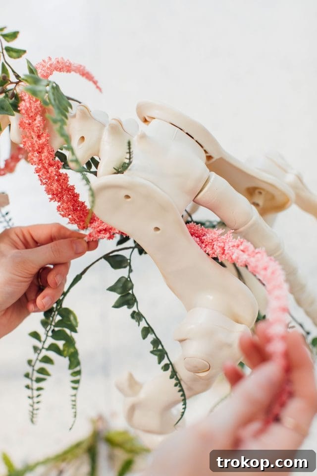 Whimsical Halloween Door Decorating Ideas 10 A close-up view of faux flowers being strung onto a unicorn skeleton, creating a spooky yet elegant Halloween decoration