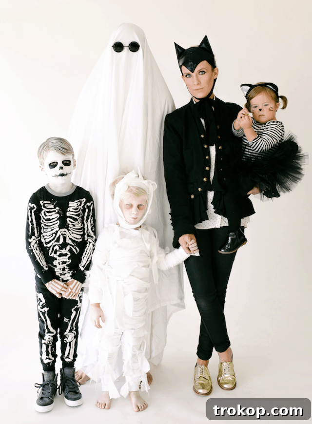 40 Spooktacular Family Halloween Costume Ideas 28 A family dressed in classic black and white Halloween costumes: ghost, black cat, mummy, and skeleton, for a spooky yet elegant look.