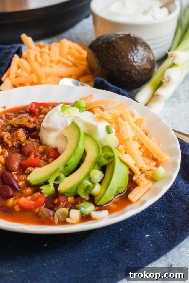Photo of the Best Easy Turkey Chili Recipe garnished with avocado, cheese and sour cream