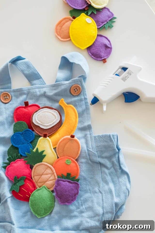 A blue baby romper, chosen as a base outfit, lays flat ready for fruit snack costume embellishments.