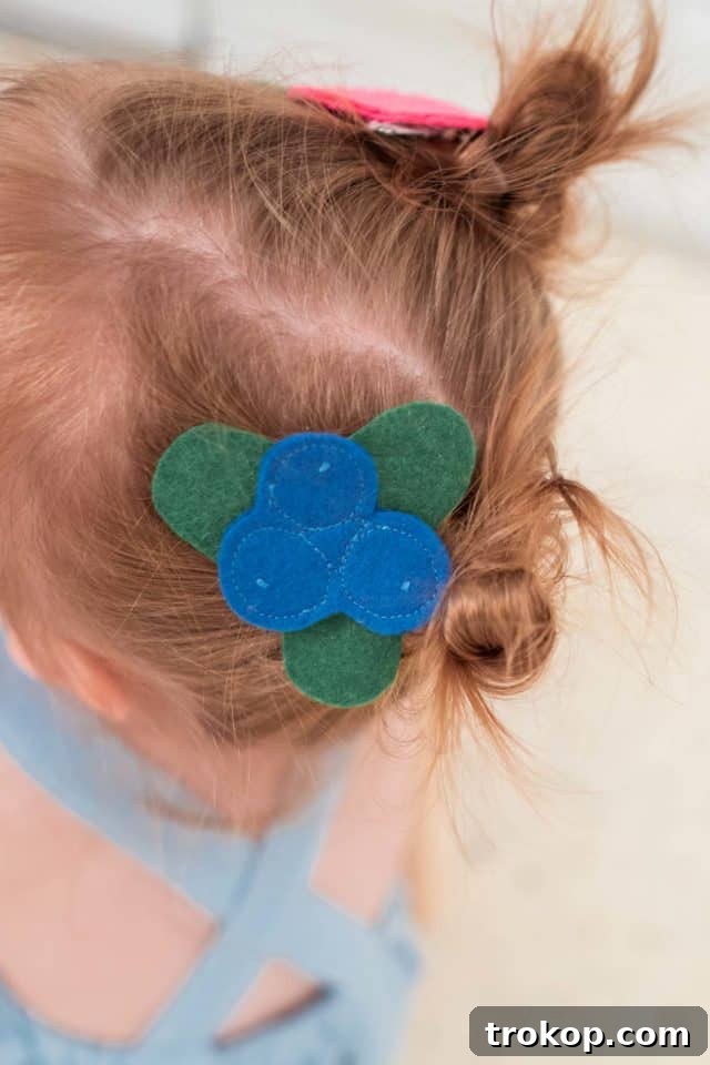 Close-up photo of colorful felt fruit glued onto metal hair clips, creating charming costume accessories.
